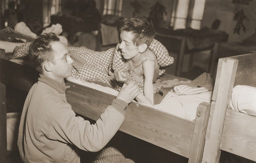 Amerykański lekarz bada jednego z ocalałych więźniów obozu w Flossenbürgu. Zdjęcie wykonane 8 maja 1945 roku (J.P. Musae/domena publiczna).