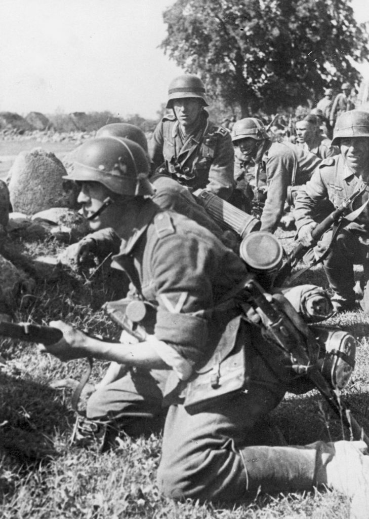 Niemiecka piechota przygotowuje się do szturmu, kryjąc się za kamieniami przy drodze. Zdjęcia wykonane w pierwszych dniach inwazji na ZSRR (domena publiczna).