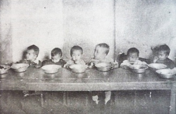 Dzieci z łagrowego sierocińca w trakcie posiłku (domena publiczna).