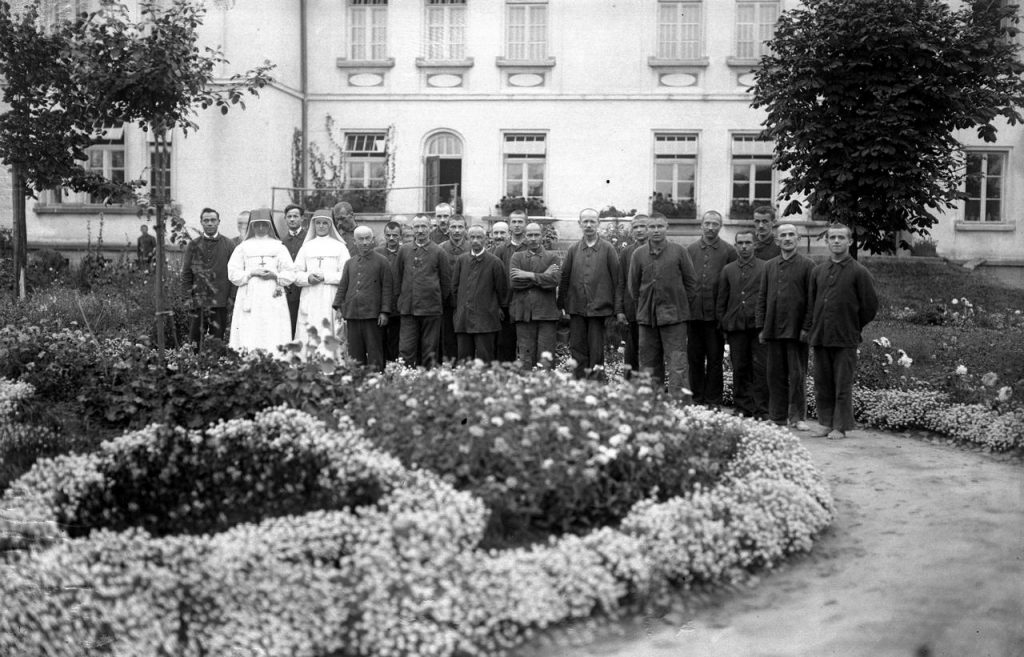 Pacjenci wraz z pielęgniarkami Szpitala dla Nerwowo i Psychicznie Chorych w Kobierzynie. Zdjęcie z sierpnia 1927 roku (domena publiczna).
