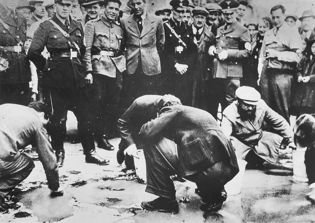 Po zajęciu Austrii naziści od razu przystapili do prześladowania tamtejszych Żydów. Na zdjęciu Żydzi zmuszani do czyszczenia chodnik w Wiedniu (domena publiczna).