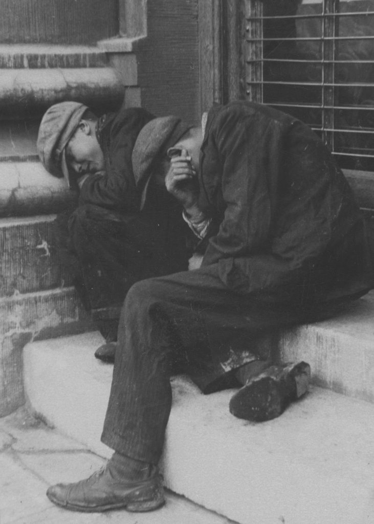 Bezrobotni mężczyźni śpiący na ulicy (domena publiczna).