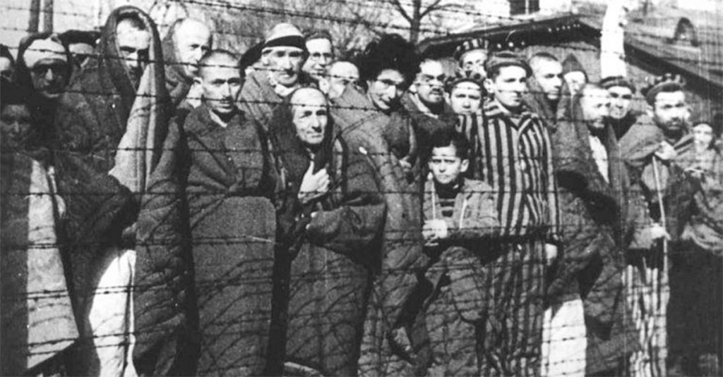 Więźniowie Auschwitz-Birkenau na zdjęciu wykonanym bezpośrednio po wyzwoleniu obozu.