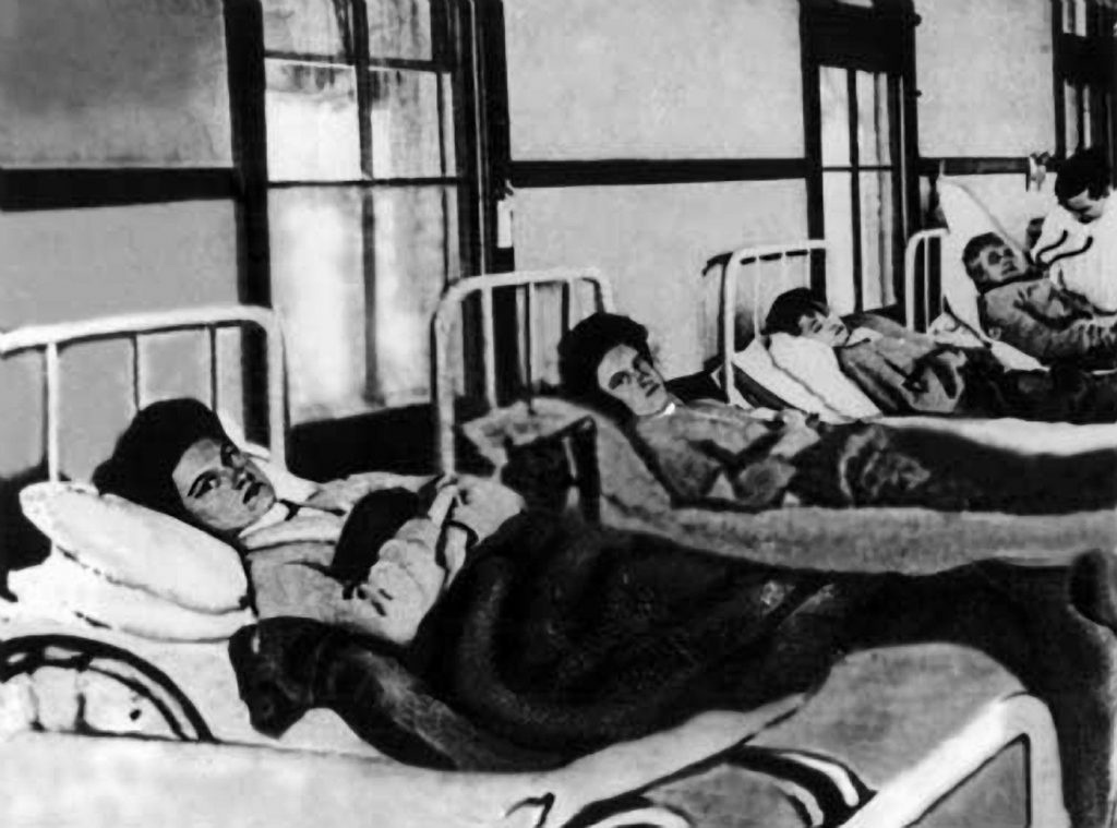 Mary Mallon (pierwsza od lewej) w szpitalnym łóżku (domena publiczna).