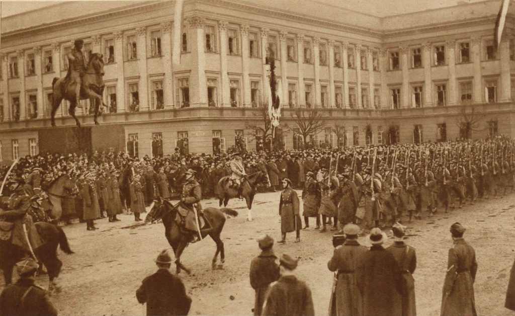 Marszałek Piłsudski odbierający defiladę na placu Saski z okazji ósmej rocznicy odzyskania niepodległości (domena publiczna).