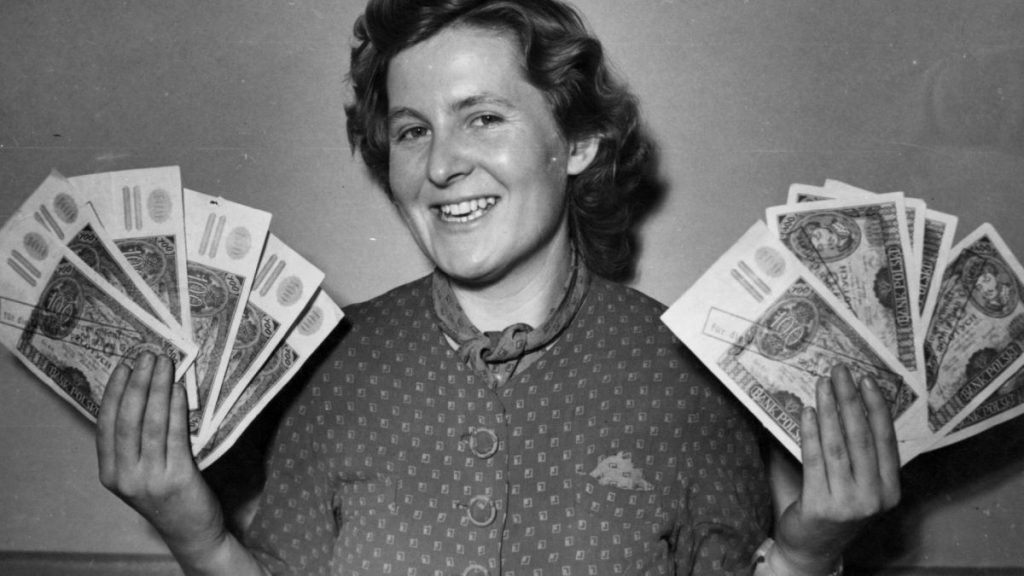 Kobieta trzymająca ostemplowane banknoty 100-złotowe.