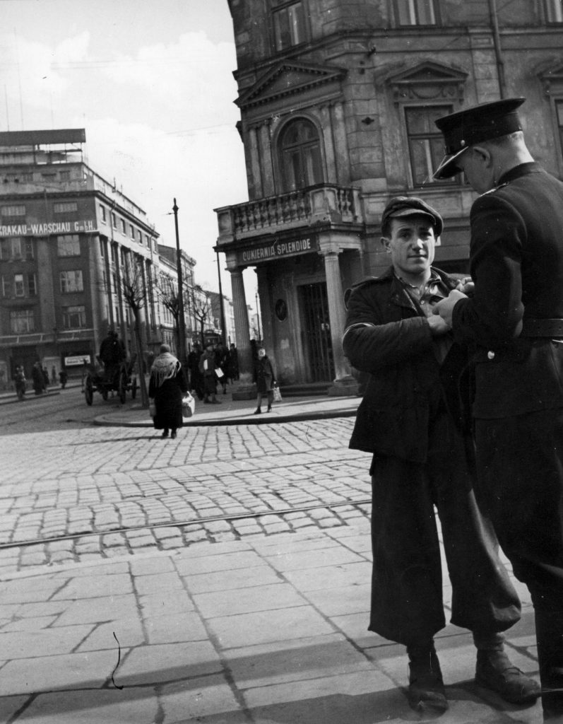 Granatowy policjant wystawiający mandant pieszemu za niewłaściwe przejście przez ulicę. Fotografia z 1940 roku (domena publiczna).