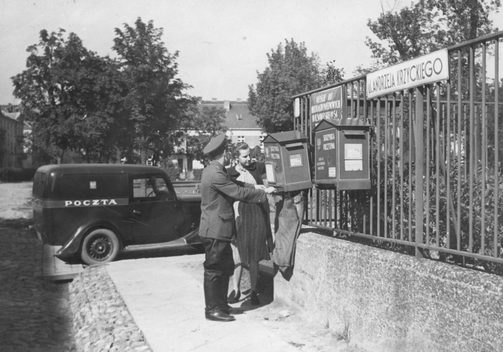 Pracownicy poczty opróżniają krzynkę pocztową na jednej z warszawskich ulic. Lata 30. XX wieku (domena publiczna).