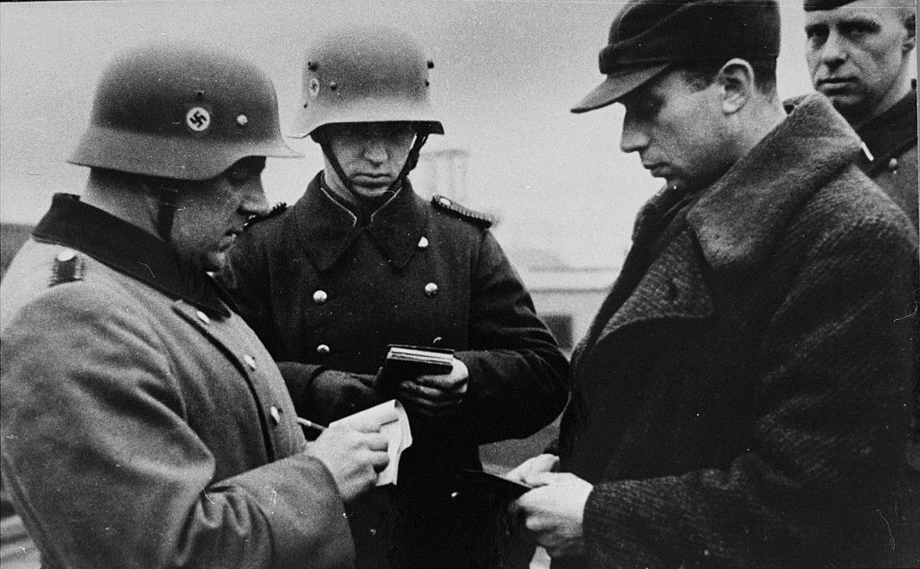 Niemieccy żołnierze kontrolujący dokumenty Żyda z krakowskiego getta (domena publiczna).