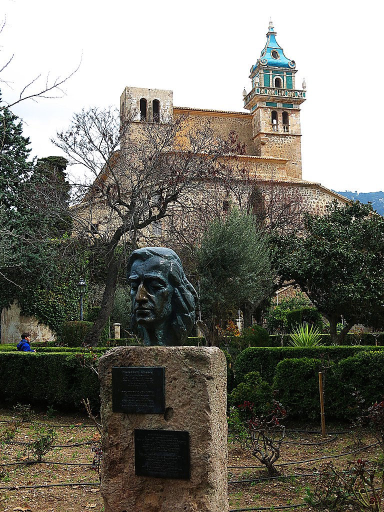 Pomnik Fryderyka Chopina w Valldemossie. W tle widoczne zabudowania poklasztorne (Enric/CC BY-SA 4.0).