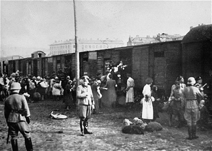 Żydzi z getta warszawskiego ładowanie do pociągu jadącego do obozu zagłady w Treblince (domena publiczna).