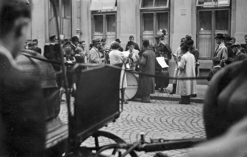 Uliczna orkiestra grająca przed kamienicą przy ul. Złotej w Warszawie. Zdjęcie z czasów okupacji (domena publiczna).