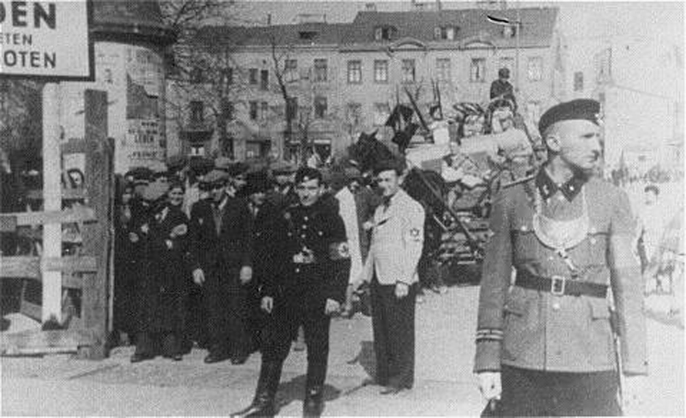 Niemieccy i żydowscy policjanci pilnujący wejścia na teren getta łódzkiego (domena publiczna).