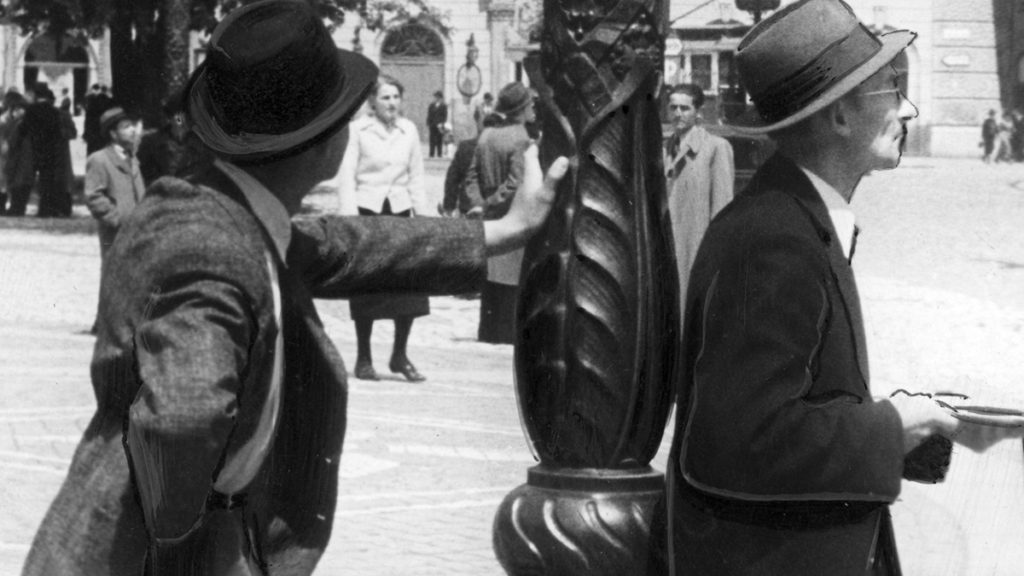 Bezrobotni mężczyźni przy latarni. Kraków, rok 1941.