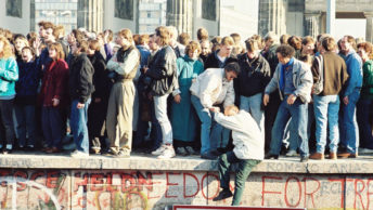 Ludzie na szczycie muru berlińskiego 9 listopada 1989 roku
